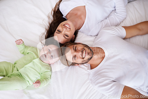 Image of Top view of portrait, mother and father with baby on bed for love, care and quality time together. Happy parents, family and newborn child relaxing in bedroom for smile, happiness and bonding at home