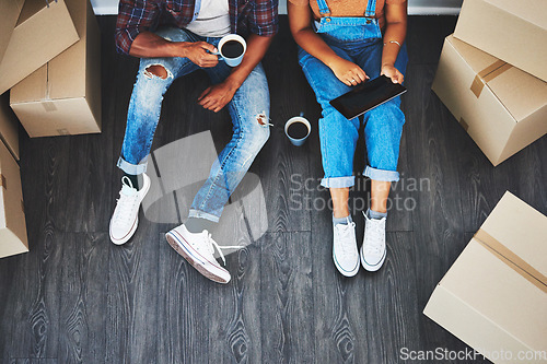 Image of Tablet, coffee and couple moving with boxes planning their new house together on living room floor. Technology, caffeine and top view of man and woman doing property research on mobile in their home.