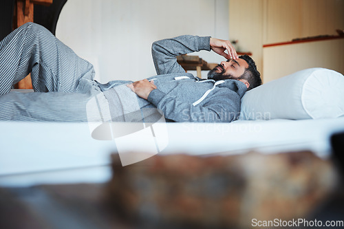 Image of Tired, sleep and a man with a headache on a bed with burnout, looking sad and depressed. Fatigue, insomnia and a person with depression, anxiety or a migraine problem in the bedroom of a house