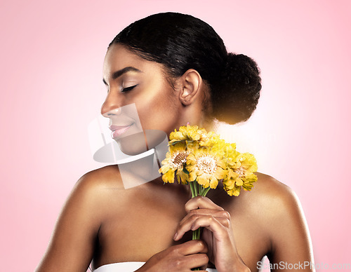 Image of Woman, face and flowers for skincare in studio, pink background and eco friendly makeup cosmetics. African model, natural beauty and yellow daisy plants for sustainability, floral blossom and perfume