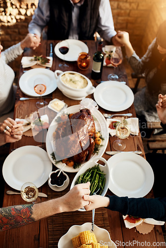 Image of Food, table and people praying and holding hands while eating together for holiday celebration. Above group of family or friends pray for thanksgiving lunch, chicken or turkey and wine drinks