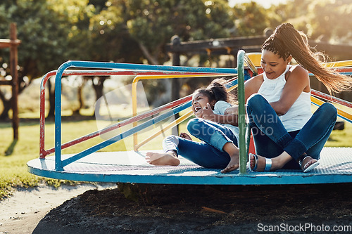 Image of Mother with daughter laughing, together on roundabout at park and playing with fun outdoor. Love, care and bonding with family happiness, woman and girl enjoying time at playground with freedom