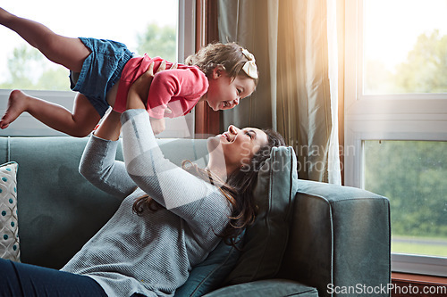 Image of Happy, mom and lifting girl on sofa in home living room and relax, bonding and quality time together or mother, love and family happiness. Child, mommy and playing game on couch in house with smile