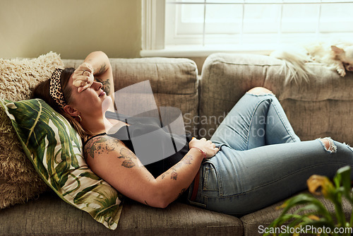 Image of Period pain, menstruation and a woman on a sofa in the living room of her home suffering from cramps. Stomach, digestion and constipation with a young female person holding her belly in discomfort