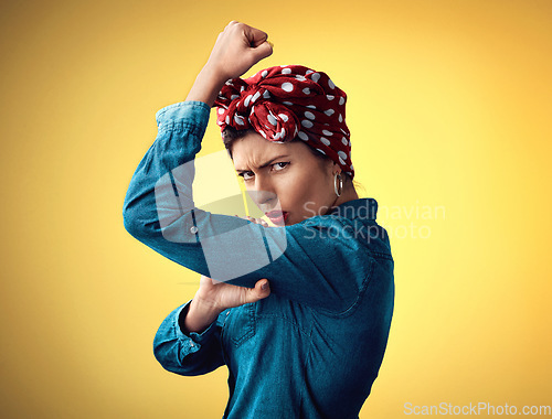 Image of Pinup girl, strong and flexing muscle portrait in studio for support, women power and fashion. Angry female person show bicep on yellow background for motivation, freedom and retro or vintage style