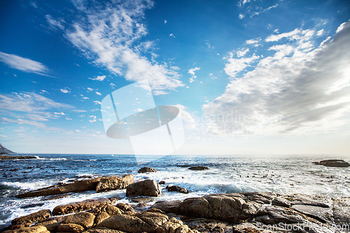 Image of Rock, ocean and nature with waves at beach for environment, landscape and blue sky. Calm, summer and seascape with sunrise on horizon at coastline for tropical, clouds and water surface