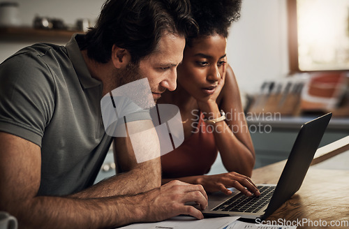 Image of Couple, finance and laptop in a kitchen for planning, budget and savings or paying bills together in their home. Interracial marriage, online and people with tax, mortgage or home loan or insurance