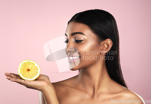 Image of Skincare, face and smile of woman with an orange in studio isolated on pink background. Fruit, natural cosmetics and Indian female model holding food for healthy diet, nutrition or vitamin c to detox