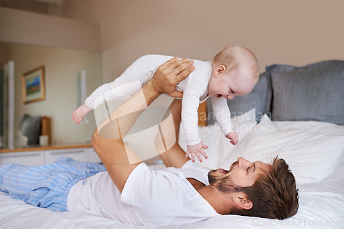 Image of Father, on bed and holding his baby girl up in the air or playful daughter and having fun in the bedroom feeling happy. Parent, kid and dad bonding or carefree and excited together in the house