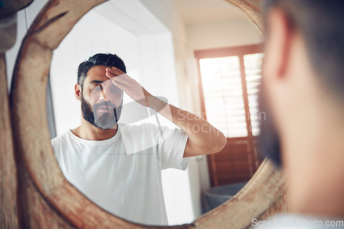 Image of Stress, headache and man by a mirror in the bathroom while doing a skincare routine in his home. Migraine, tired and mature male person doing a health dermatology face treatment in his modern house.