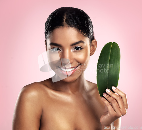 Image of Portrait, happy woman and leaves for natural beauty in studio, pink background and eco friendly vegan cosmetics. Face, african model and healthy skincare of plants, green leaf and sustainable shine