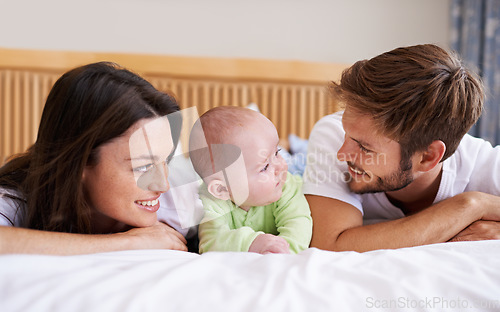 Image of Happy family, mother and father with baby on bed for love, care and fun quality time together at home. Parents, cute newborn child and bonding to relax in bedroom for support, nurture and happiness