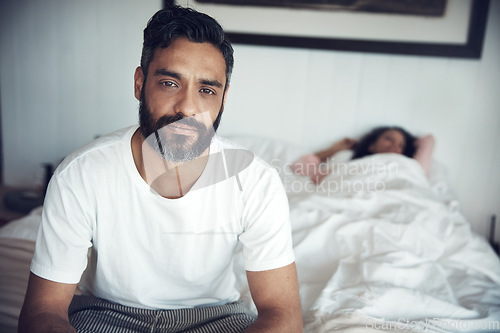 Image of Sad, depression and portrait of a man on a bed with wife sleeping in the morning. Upset, depressed and a mature male person looking tired, frustrated or unhappy with a woman in the bedroom for sleep