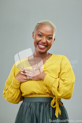 Image of Portrait, thank you and hands on chest of happy woman in studio with love sign on wall background. Face, smile and hand on heart by female person showing gratitude, kindness and self care or honesty