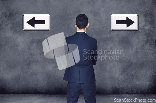 Image of Back, arrow and direction with a business man planning or brainstorming a decision while in doubt on a wall background. Confused, challenge or strategy with a male employee thinking of a solution