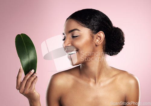 Image of Woman, smile and leaf of skincare in studio, pink background and eco friendly facial cosmetics. Face, happy and african model with natural beauty, green plants and sustainability of vegan dermatology