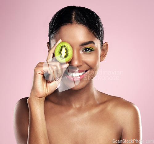 Image of Portrait, woman and kiwi for beauty in studio, pink background and healthy vitamin c cosmetics. Face of happy african model, green fruits and nutrition of natural skincare, organic benefits and glow