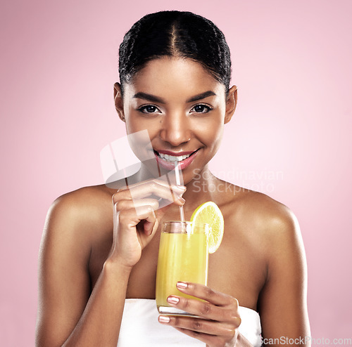 Image of Portrait, woman and orange juice in studio for beauty, healthy nutrition or vitamin c benefits on pink background. Happy african model, glass and fruit cocktail drink, citrus smoothie or natural diet