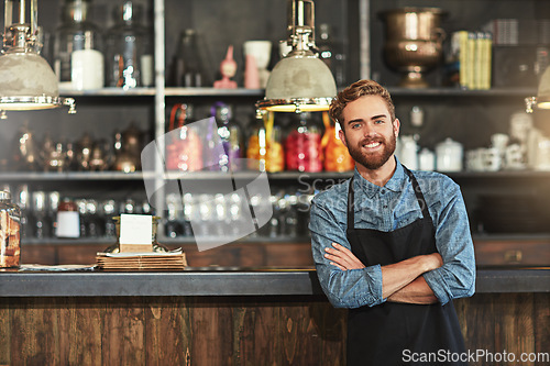 Image of Happy, crossed arms and portrait of male barista standing by the counter in his startup cafeteria. Smile, success and young man small business owner with confidence in coffee shop or restaurant.