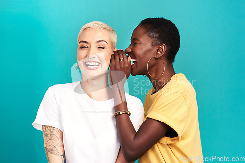 Image of Whisper, secret and girl friends portrait with privacy, laugh and gossip in a studio. Blue background, women and smile of a female person with diversity and funny news telling a story and listening