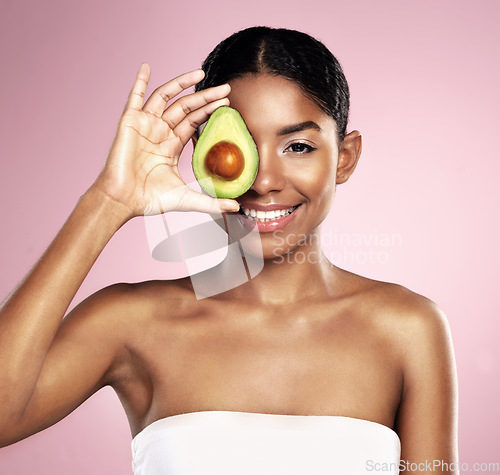 Image of Avocado, portrait and beauty of woman in studio, pink background and aesthetic glow. Happy african model, natural skincare and fruit for sustainable cosmetics, vegan dermatology and facial benefits