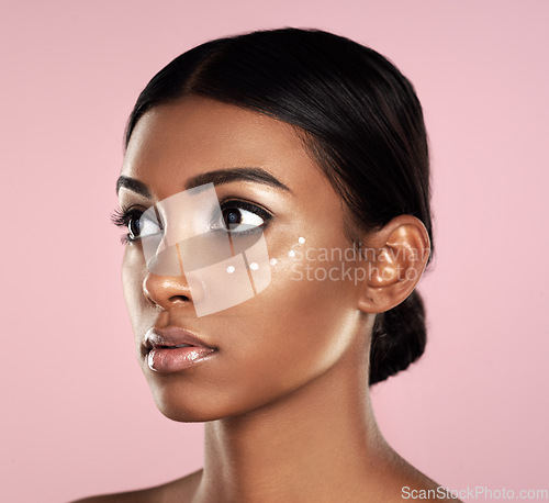 Image of Thinking, skincare or beauty of woman with eye cream in studio isolated on pink background. Dermatology, creme cosmetics and serious Indian female model with moisturizer retinol for healthy face skin