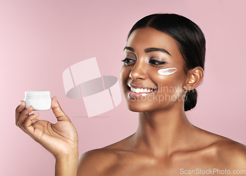 Image of Skincare, smile and woman with cream container in studio isolated on a pink background. Product, dermatology creme and Indian female model holding lotion, moisturizer and cosmetics for healthy skin.