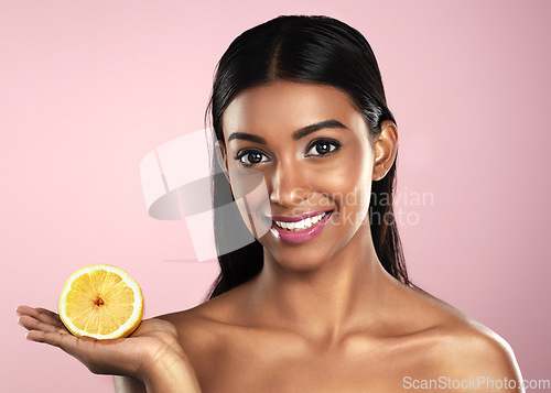 Image of Face, skincare and smile of woman with an orange in studio isolated on pink background. Fruit, natural cosmetics and portrait of Indian female model with food for healthy diet, vitamin c or nutrition