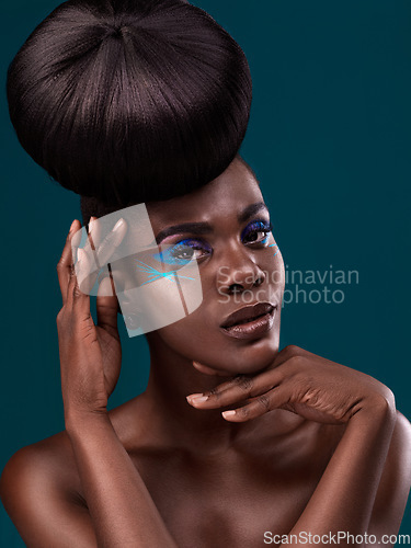 Image of Portrait, hair and cosmetics with an african woman in studio on a blue background for beauty or makeup. Eyeshadow, haircare and fashion with an attractive young female model at the salon for style