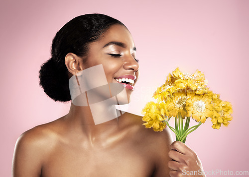 Image of Happy woman, yellow flowers and natural skincare in studio, pink background and eco friendly makeup cosmetics. African model, beauty and smile with daisy plants, happiness and glow of floral facial