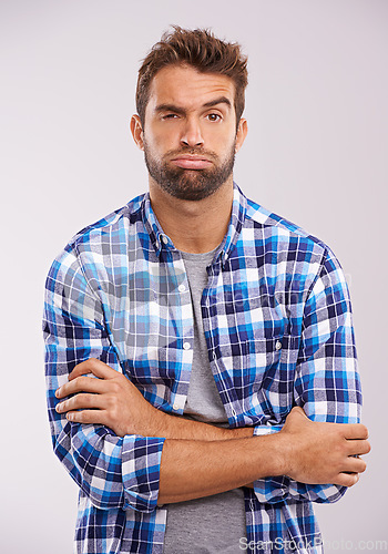 Image of Frustrated, tired and portrait of a man with arms crossed in a studio feeling annoyed and bored. Isolated, white background and male model with upset face and grumpy with casual fashion and doubt