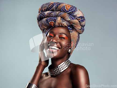 Image of Head scarf, black woman laugh and portrait with African beauty and makeup in a studio. Isolated, grey background and traditional fashion with a female model pride with culture cosmetics and jewelry