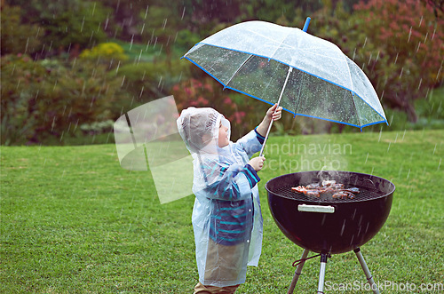 Image of Weather, nature and boy with a grill, rain and wellness with safety, cover and winter outfit. Bbq, male child or kid with umbrella, cold or young person with food, raincoat or outdoor with protection