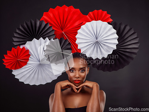 Image of Portrait, makeup and black woman with origami fans in studio isolated on a dark background. Serious face, beauty cosmetics and skincare of female model with traditional Japanese paper art for culture