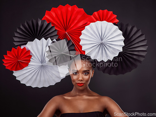 Image of Face, makeup and black woman with origami fans in studio isolated on a dark background. Serious portrait, beauty cosmetics and skincare of female model with traditional Japanese paper art for culture