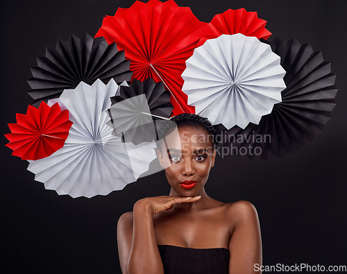 Image of Face, aesthetic and black woman with origami fans in studio isolated on a dark background. Beauty portrait, makeup cosmetics and skincare of female model with traditional Japanese art for fashion hat