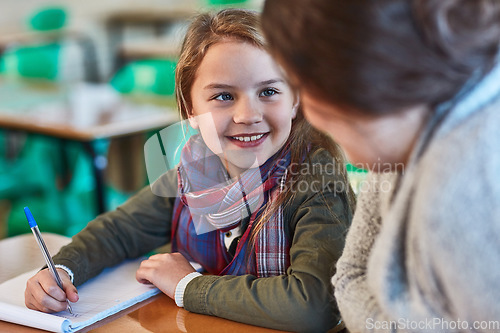 Image of School, education and a student girl with her teacher in the classroom for learning or child development. Study, writing and smile with a happy young female pupil in class with a woman educator