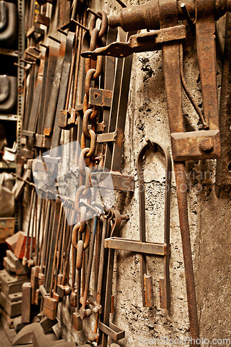 Image of Steel, tools and workshop with blacksmith workplace and industrial factory wall background. Artisan, retro and metal tool for manufacturing, warehouse and brass forge industry equipment hanging