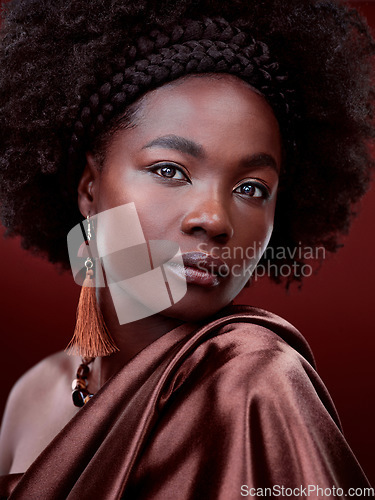 Image of Natural beauty, face and black woman with fashion in studio isolated on a red background. Portrait, makeup cosmetics and serious African model with stylish outfit, traditional jewelry and aesthetic.