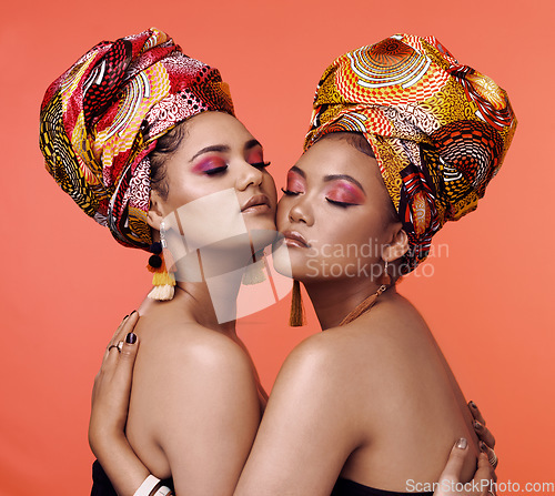 Image of Fashion, beauty and African women hug on orange background with cosmetics, makeup and accessories. Glamour, luxury and female people with exotic jewelry, traditional style and head scarf in studio