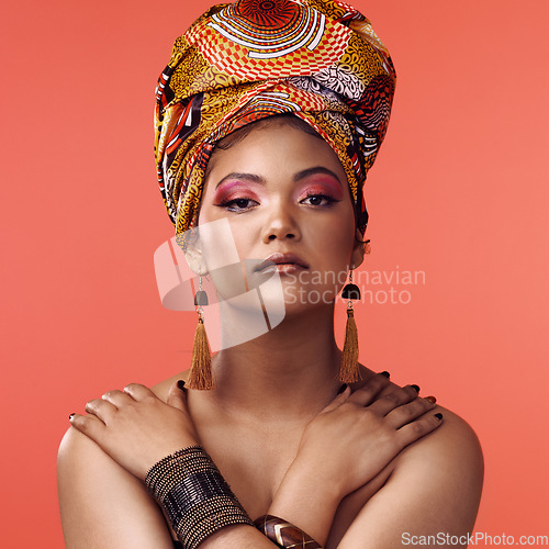 Image of African fashion, beauty and portrait of woman on orange background with cosmetics, makeup and accessories. Glamour, model and face of female person with exotic jewelry, traditional style and scarf