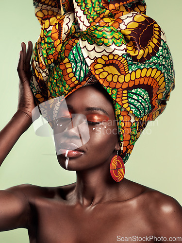 Image of Culture, beauty and black woman in head wrap in studio with cultural, glow and cosmetics on green background. Face, makeup and African female model with turban, tradition and confidence isolated