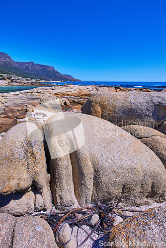 Image of Scenic view of the rocky coastline of Camps Bay, Cape Town. Boulders in lining the ocean in the Western Cape, South Africa. Relaxing seaside views of the city of and mountains