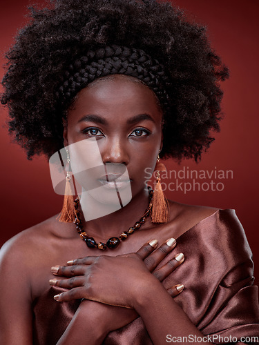 Image of Portrait, beauty and black woman with traditional fashion in studio isolated on a red background. Natural face, makeup cosmetics and serious African model with stylish outfit, headband and culture.