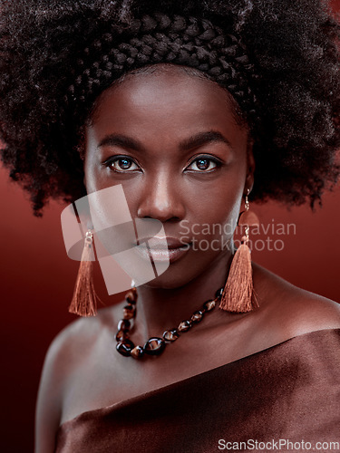 Image of Face, portrait and black woman with fashion in studio isolated on a red background. Natural beauty, makeup cosmetics and serious African model with stylish outfit, traditional jewelry and culture.