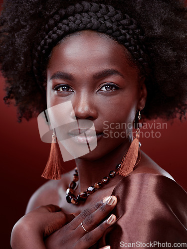 Image of Natural beauty, portrait and black woman with fashion in studio isolated on a red background. Face, makeup cosmetics and serious African model with stylish outfit, traditional jewelry or aesthetic.