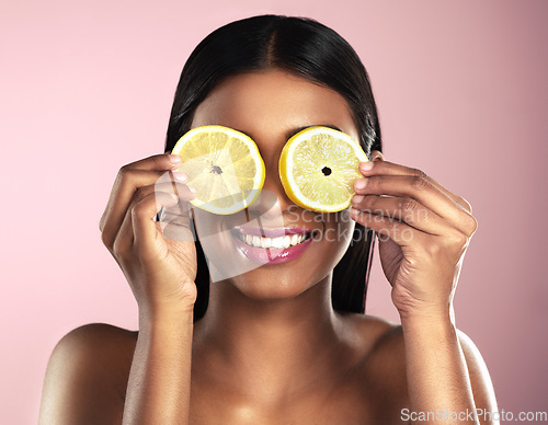 Image of Face, skincare and smile of woman with orange slices in studio isolated on a pink background. Fruit, natural cosmetics and Indian female model holding food for healthy diet, nutrition or vitamin c.