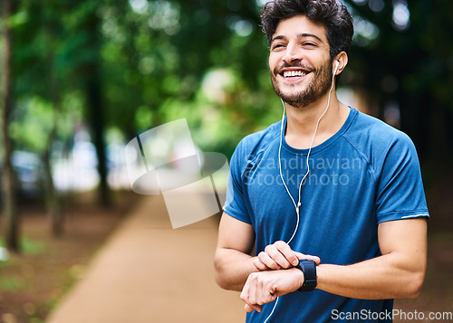 Image of Fitness, music and man with a watch for time, running progress and heart results in a park. Smile, thinking and a male athlete listening to a podcast or audio while checking notification on a device