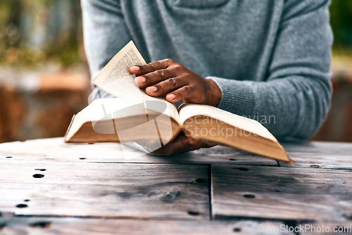 Image of Hands, religion and a man reading the bible at a table outdoor in the park for faith or belief in god. Book, story and spiritual with a male christian sitting in the garden for learning or worship