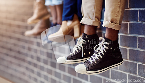 Image of Brick wall, student sneakers and friends outdoor on university campus together with shoes. Relax, youth and foot at college with people legs ready for education, study and urban feet while sitting